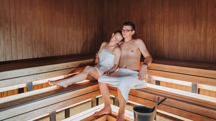A young couple sitting side by side in a sauna