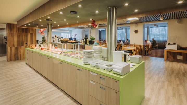 Moodne ja avar söögisaal, kus on pakutakse bufee-stiilis toitlustust, toolid-lauad ja suured aknad.